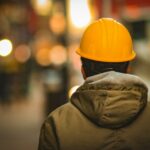 person in yellow hard hat and brown jacket